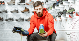Un homme assis avec une sneaker dans chaque main.